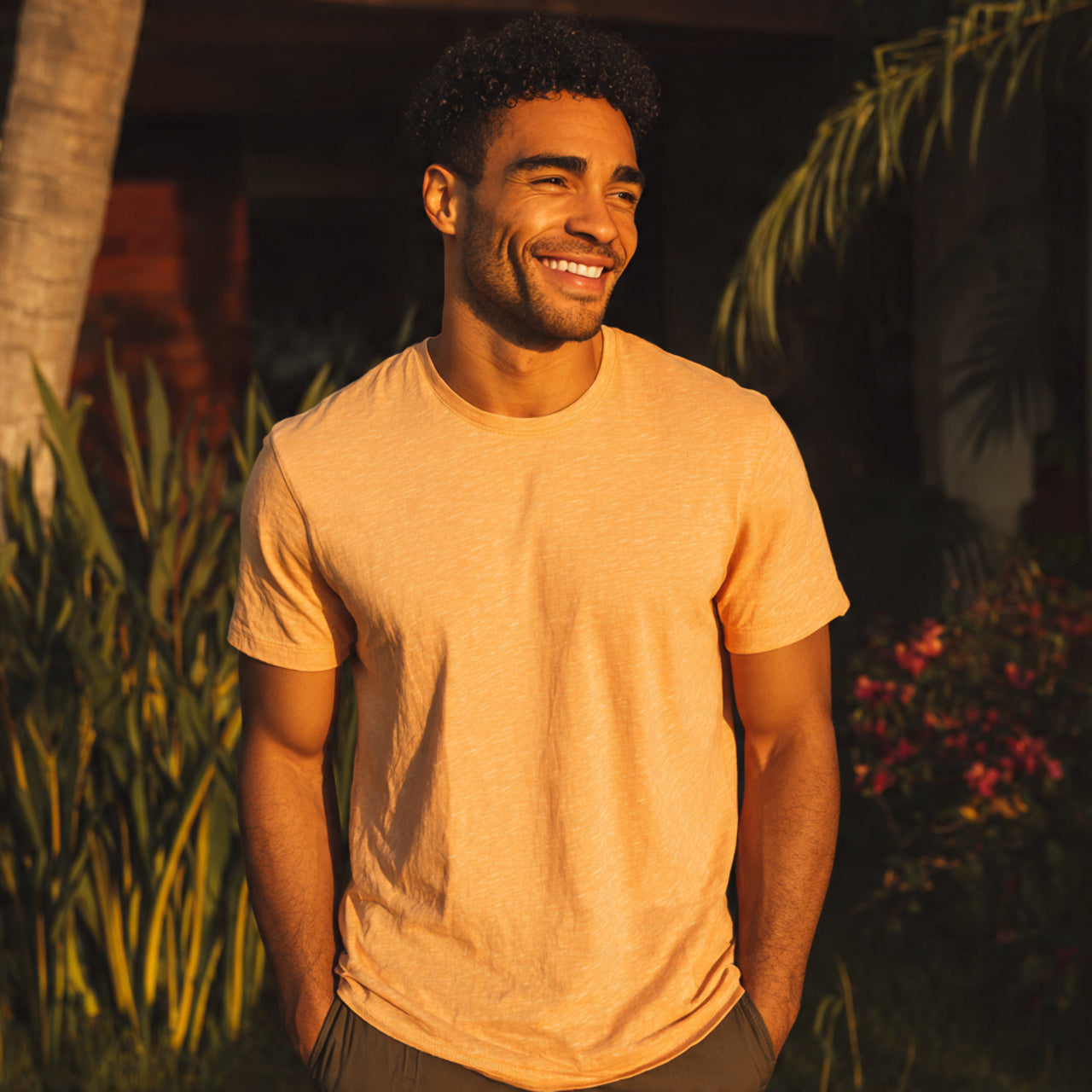 “Male model wearing fitted t-shirt at a casual house party or outdoor social gathering, warm sunset tones, natural smiles, authentic lifestyle look, no text or logos.”